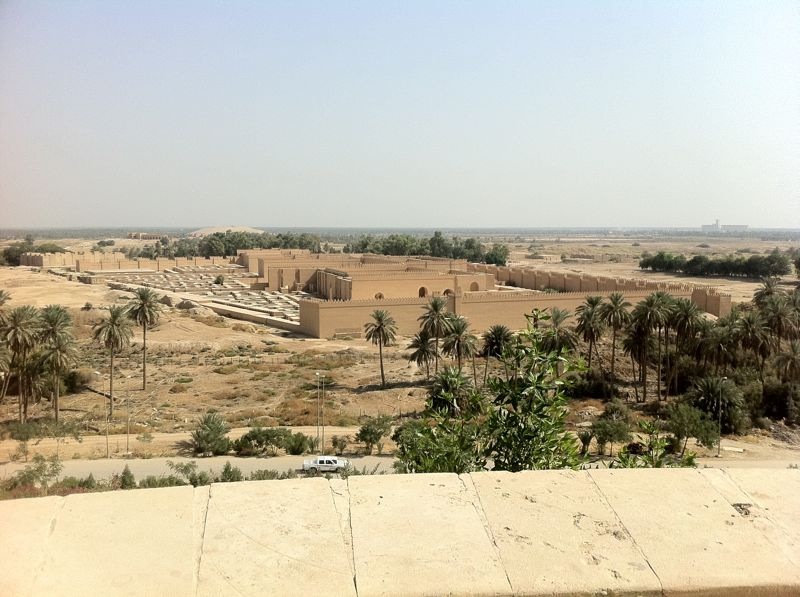 image illustrating the archaeological site of babylon in iraq. a reconstructed and preserved large brick building appears in the centre of the image, from a distance