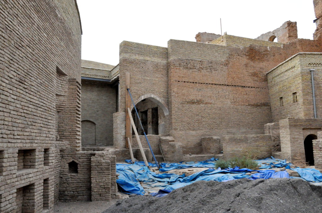 Image illustrating restoration work carried out in the historical citadel of erbil in the kurdistan region of iraq. plastic sheets appear on the ground surrounded by brick structures and wall containment scaffolding