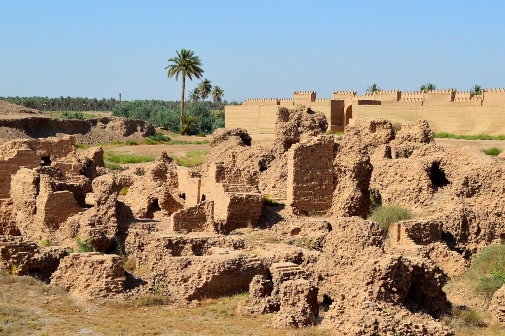 image illustrating the archaeological ruins of babylon in Iraq. remains of brick structures appear in the foreground and reconstructed brick walls appear in the background